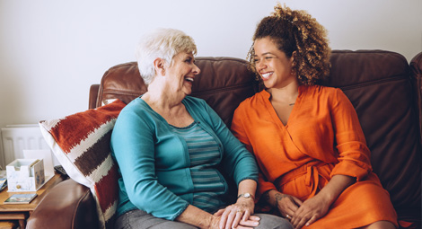 Two women sat together on a sofa laughing